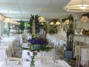 un restaurante con mesas blancas y sillas con flores. en Hotel Atlantic, en Marina di Carrara