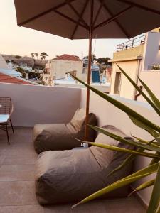einen Balkon mit zwei Sitzsäcken und einem Sonnenschirm in der Unterkunft Gaia Luxury Rooms in Rethymno