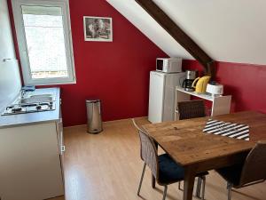kuchnia i jadalnia z drewnianym stołem i czerwoną ścianą w obiekcie La maison du Chêne 1 w mieście Miniac-Morvan