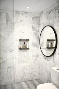 La salle de bains est pourvue d'un miroir et de murs en marbre blanc. dans l'établissement Bright apartment in the hills of Elviria, à Malaga