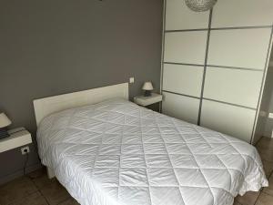 1 dormitorio con 1 cama blanca y 2 mesitas de noche en La maison du Chêne 2 en Miniac-Morvan