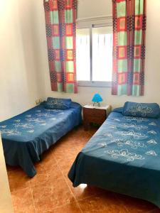 een kamer met 2 bedden en een raam met gordijnen bij Blue holiday in Oued Laou