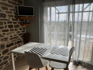 una mesa y sillas blancas en una habitación con ventana en La maison du Chêne 2 en Miniac-Morvan