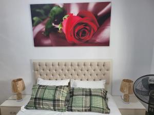 a picture of a red rose above a bed at Appartement haut standing avec piscine in Dakar