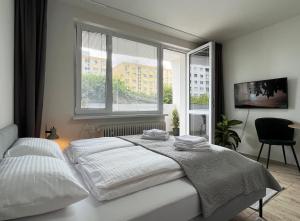 a white bedroom with a bed and a window at New cozy studio, private parking in Bratislava