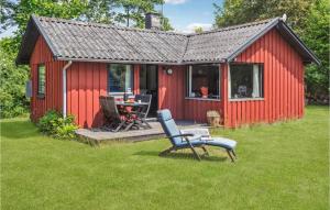 a red shed with a table and a chair in the grass at 3 Bedroom Gorgeous Home In Nakskov in Nakskov