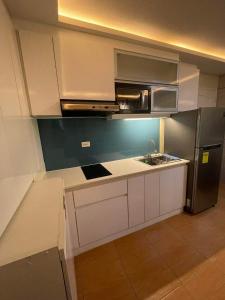 een keuken met witte kasten en een roestvrijstalen koelkast bij San Remo Oasis and Bamboo Bay Condominium in Mandaue-stad