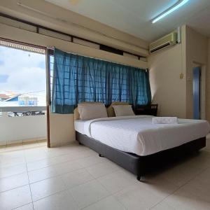 a bedroom with a bed and a large window at Kota Lodge Guest House in Malacca