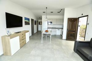 a living room with a television and a kitchen at Villa Sotavento Adults Only in Playa Jandia