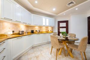 a kitchen with white cabinets and a table and chairs at Palm Jumeirah Beachfront Private Villa with swimming pool in Dubai