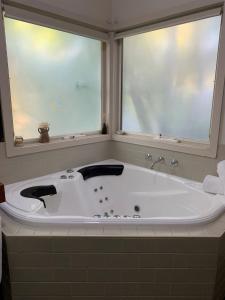 baño con bañera grande y ventana en Two Truffles Cottage Accommodation, en Yarra Glen