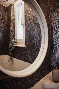 uma casa de banho com um espelho redondo e um lavatório em Cozy Dreams: Deluxe 2-Zimmer-Apartment -Küche em Nurembergue
