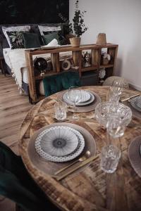 a wooden table with plates and wine glasses on it at Cozy Dreams: Deluxe 2-Zimmer-Apartment -Küche in Nürnberg