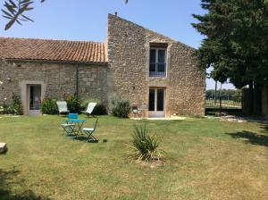 a stone house with two chairs and a table in a yard at Le Mas des Figuiers in Donzère