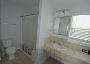 ein Bad mit einem Waschbecken, einem WC und einem Fenster in der Unterkunft Oceanfront vacation property - West in Emerald Isle