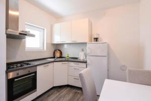 a kitchen with white cabinets and a white refrigerator at Holiday house with a parking space Dingac - Pristranj, Peljesac - 660 in Trstenik