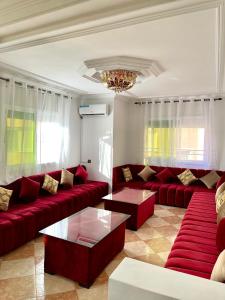 a living room with red couches and a chandelier at Apartamento Al Boustane-nador aljadid in Nador