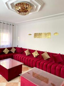 a living room with a red couch and a chandelier at Apartamento Al Boustane-nador aljadid in Nador