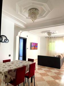 a dining room with a table and chairs and a chandelier at Apartamento Al Boustane-nador aljadid in Nador