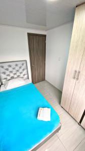 sypialnia z niebieskim łóżkiem i drewnianymi drzwiami w obiekcie Apartahotel222 Pereira 403 w mieście Pereira