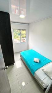 a bedroom with a blue bed and a window at Apartahotel222 Pereira 403 in Pereira