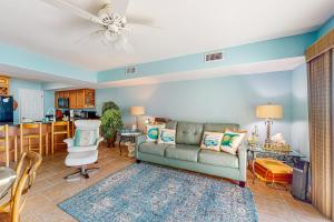 a living room with a couch and a kitchen at Sandcastle #6F in Dauphin Island