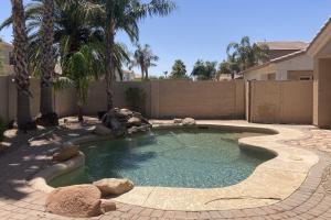 a small swimming pool in a yard with palm trees at Riviera Retreat in Sun Lakes