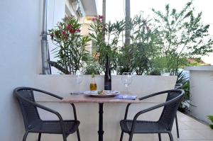 une table avec deux chaises et une assiette de nourriture et de verres à vin dans l'établissement Apartments with a parking space Preko, Ugljan - 21491, à Preko