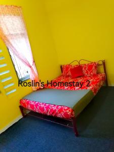 Schlafzimmer mit einem Bett mit roten Kissen und einem Fenster in der Unterkunft Roslin's Homestay 2 in Kota Bharu