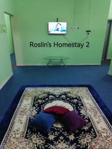 Zimmer mit einem Bett auf einem Teppich und einem TV in der Unterkunft Roslin's Homestay 2 in Kota Bharu