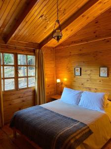 a bedroom with a bed in a wooden cabin at Rancho el Chilcal Cabañas con vista al rio in San Alfonso