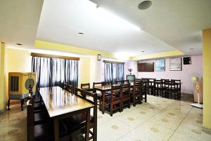 una sala da pranzo con tavoli e sedie in legno di Gautam Hotel a Varanasi