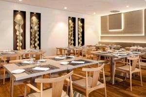 une salle à manger avec des tables et des chaises en bois dans l'établissement AC Hotel San Cugat by Marriott, à Sant Cugat del Vallès