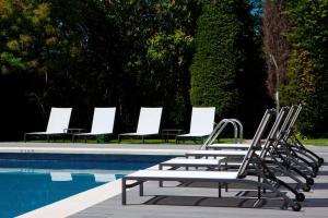 una fila de tumbonas junto a una piscina en AC Hotel San Cugat by Marriott, en Sant Cugat del Vallès