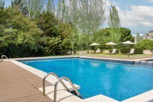 - une piscine avec des chaises longues et des parasols dans l'établissement AC Hotel San Cugat by Marriott, à Sant Cugat del Vallès