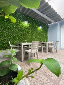 Habitación con mesas, sillas y una pared verde. en Hostal Casa Jardin Cartagena en Cartagena de Indias