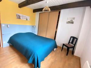 1 dormitorio con 1 cama azul y 1 silla en Cottage, Plogonnec, en Plogonnec