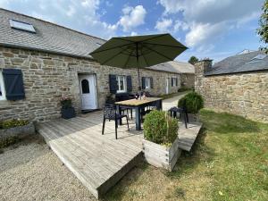 una terraza de madera con mesa y sombrilla en Cottage, Plogonnec, en Plogonnec