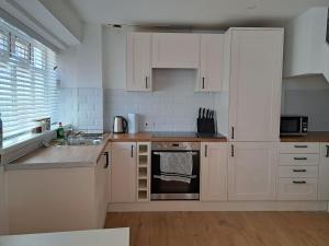 a kitchen with white cabinets and a stove top oven at Modern city house in Southampton