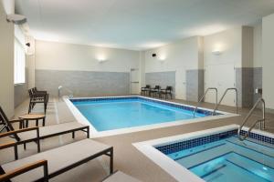 una gran piscina con 2 sillas y una mesa en Courtyard by Marriott Nanaimo, en Nanaimo