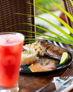 a plate of food with meat and rice and a drink at Pousada Eclipse Paraty in Paraty