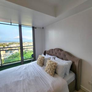 マニラにあるSuite M - 1 Bedroom Condo at Azure Residencesのベッドルーム1室(大きなベッド1台、大きな窓付)