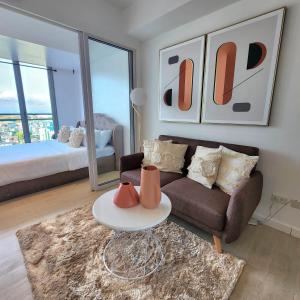 Suite M - 1 Bedroom Condo at Azure Residences في مانيلا: غرفة معيشة مع أريكة وطاولة
