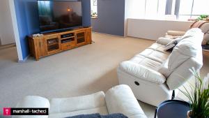 ein Wohnzimmer mit einem weißen Sofa und einem Fernseher in der Unterkunft Bermagui jewel holiday house 5 Bedroom Uninterrupted views central location Bermagui Linen & Wifi Provided in Bermagui