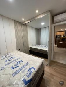 een slaapkamer met een groot bed en een spiegel bij Novinho em Camboriú in Balneário Camboriú