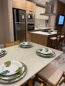 een keuken met een witte tafel met borden erop bij Novinho em Camboriú in Balneário Camboriú