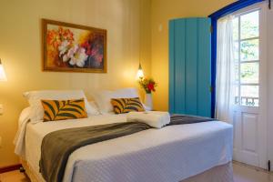 a bedroom with a large white bed with a window at Pousada Eclipse Paraty in Paraty