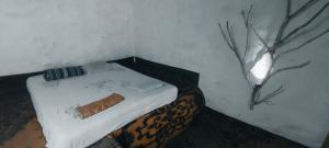ein kleines Bett in einem Zimmer mit einem Baum in der Unterkunft Eco Lodge Meemure & Adventure Park in Mimure