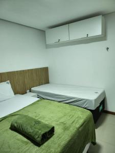 Apt 202 e 203 no ZUPPOLINI GARDEN HOTEL Bananeiras PB في بانانيراس: سريرين في غرفة صغيرة مع ملاءات خضراء