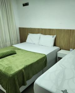Apt 202 e 203 no ZUPPOLINI GARDEN HOTEL Bananeiras PB في بانانيراس: سريرين في غرفة صغيرة بها